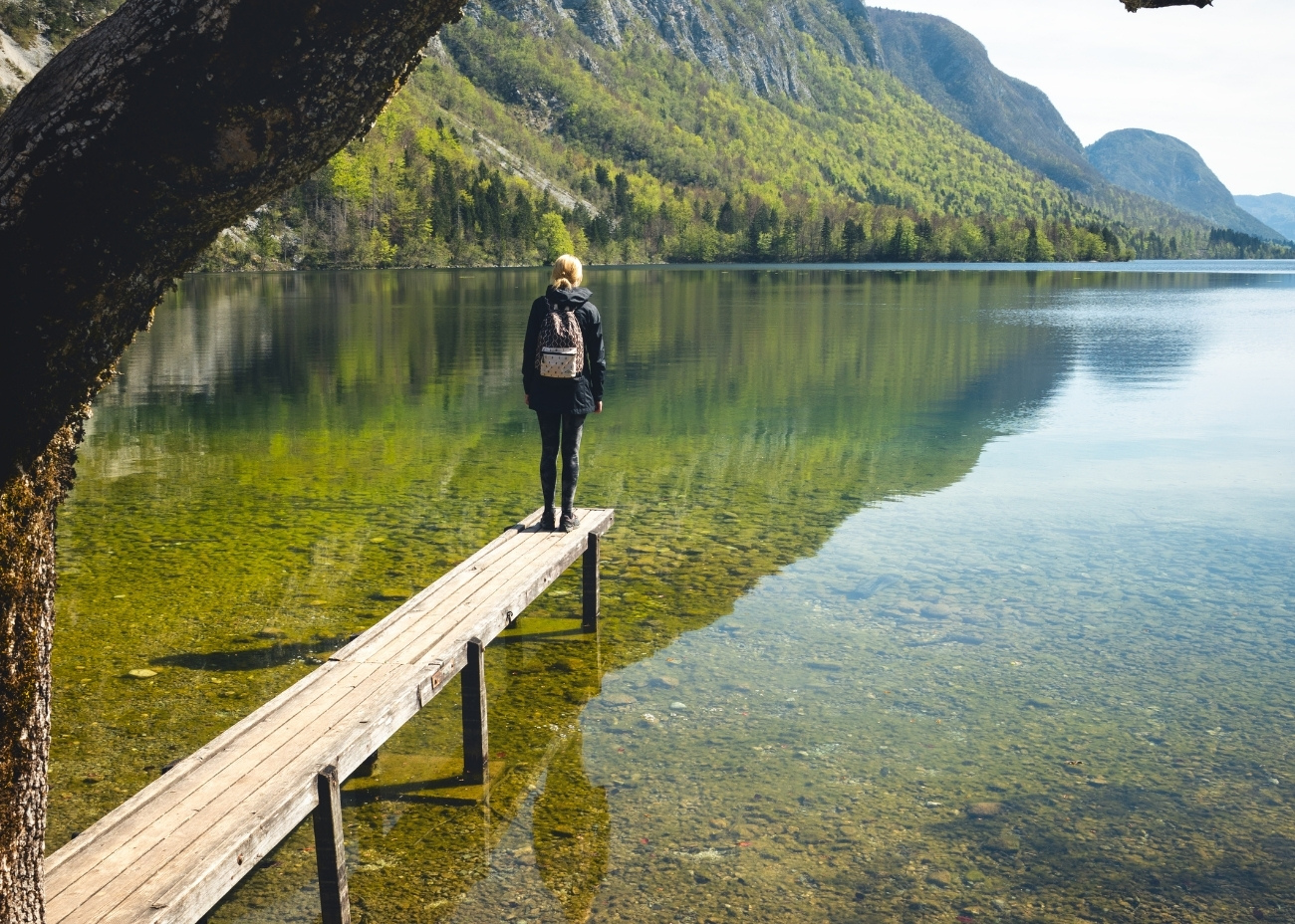 woman standing on a dock looking at the lake and mountains